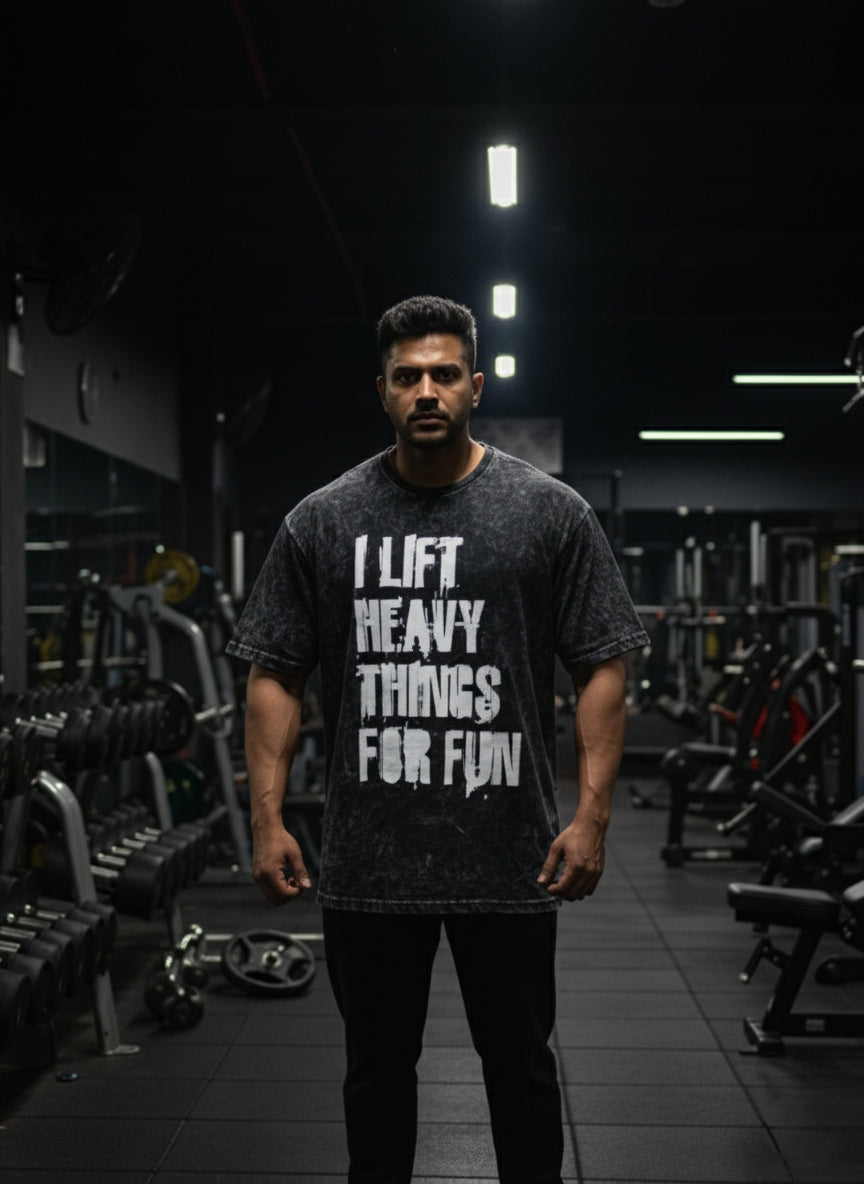 Man wearing Manmaker t-shirt with a gym quote in a darkly lit gym.