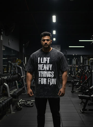 Man wearing Manmaker t-shirt with a gym quote in a darkly lit gym.