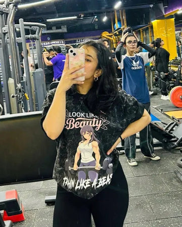Person taking a selfie in a gym wearing Manmaker t-shirt with a graphic design.